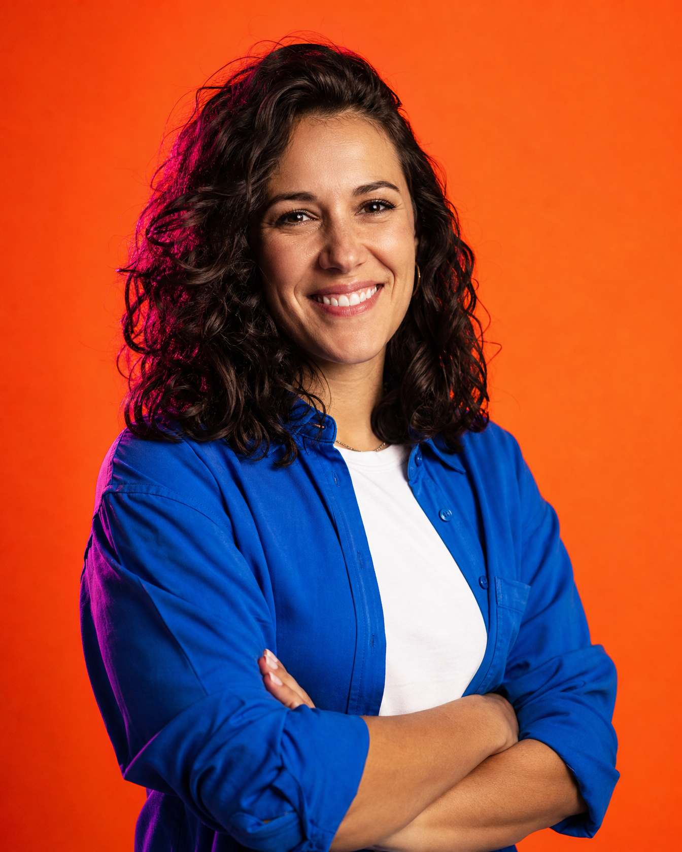 Vivid design lead, arms crossed, smiling, on a tangerine backdrop