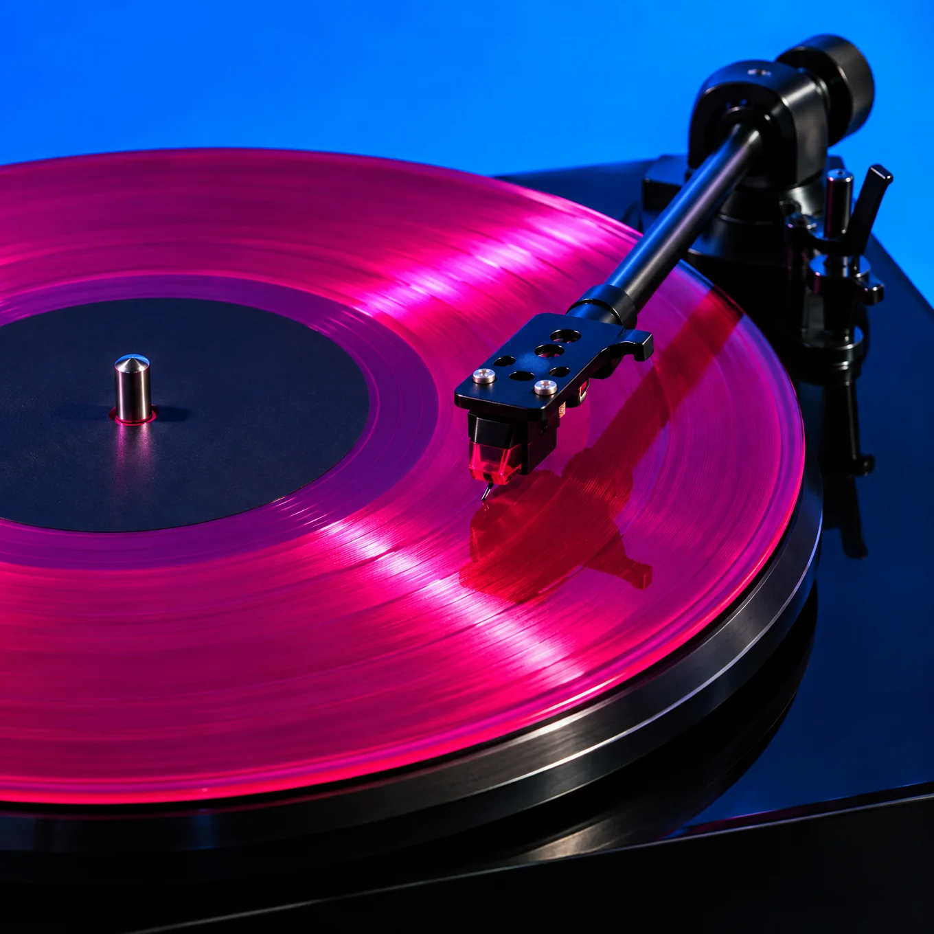Turntable with a translucent hot magenta record under electric blue light